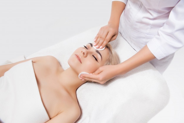 Doctor beautician cleanses the skin woman with a sponge in beauty salon. perfect cleaning - spa treatment skincare face. skin care, beauty, and spa concept